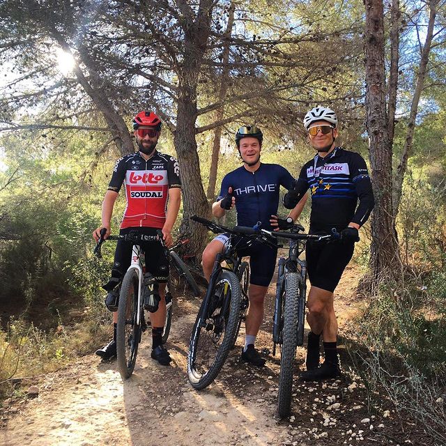 Three cyclists with full gear on posing on their bikes on a dirt road in nature.